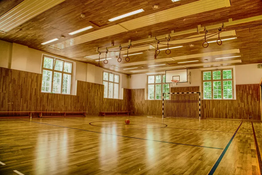 Leere Turnhalle mit Holzboden, Ringen und Handballtor